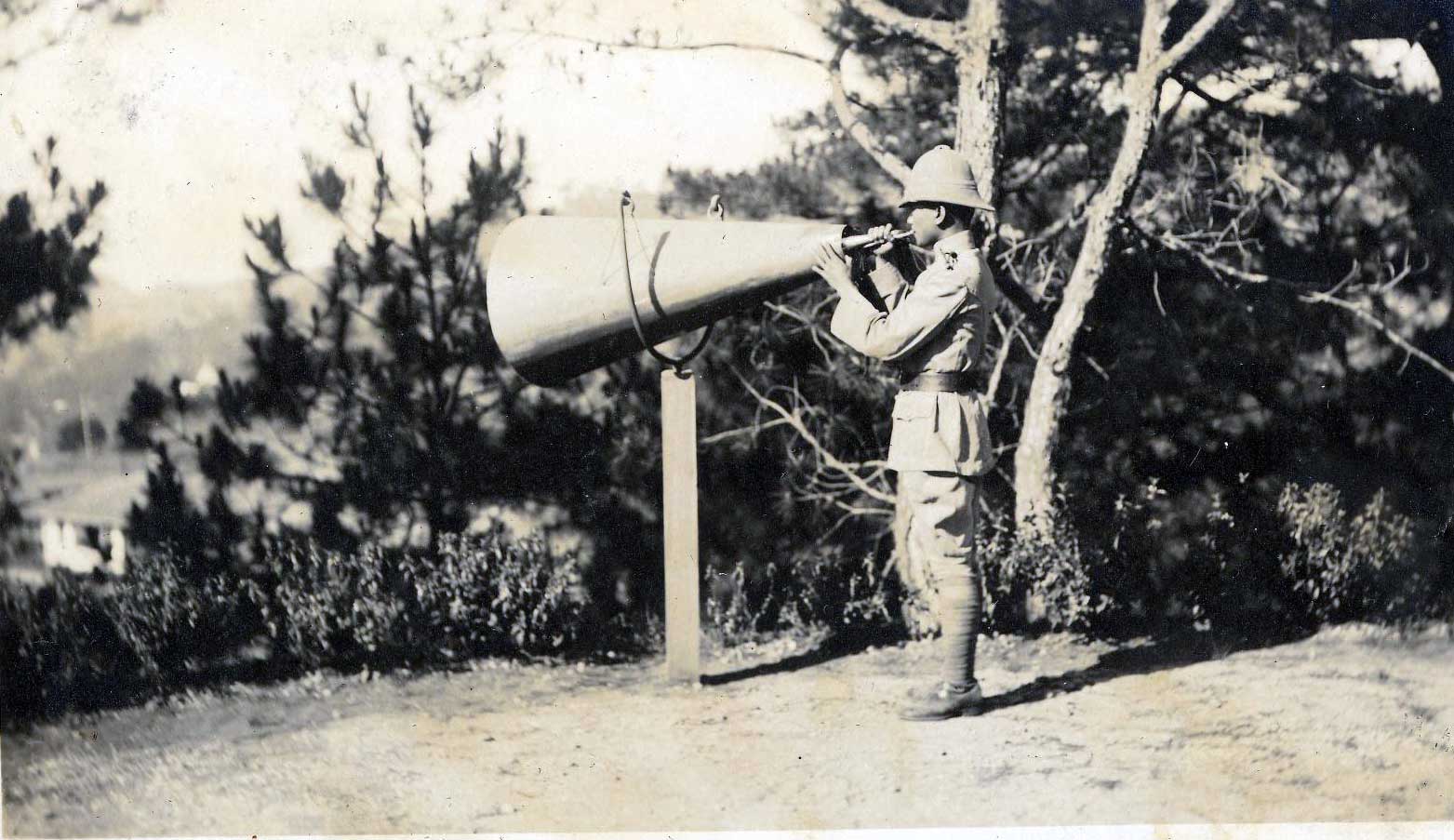 Featured photograph of a Filipino soldier blowing a horn to call for formation, from the University of Michigan Special Collections Library.